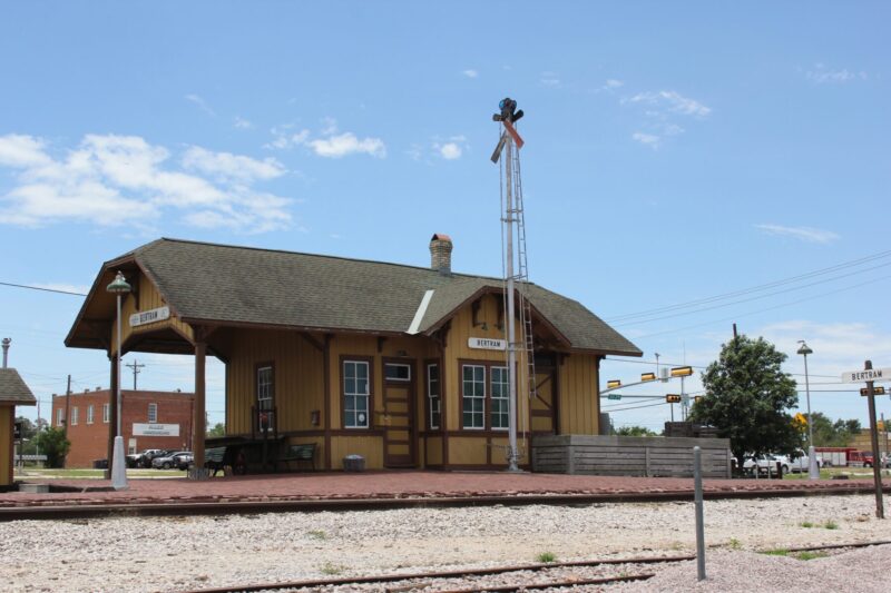 Historic Train Depot with Library in Background in Bertram, Texas.